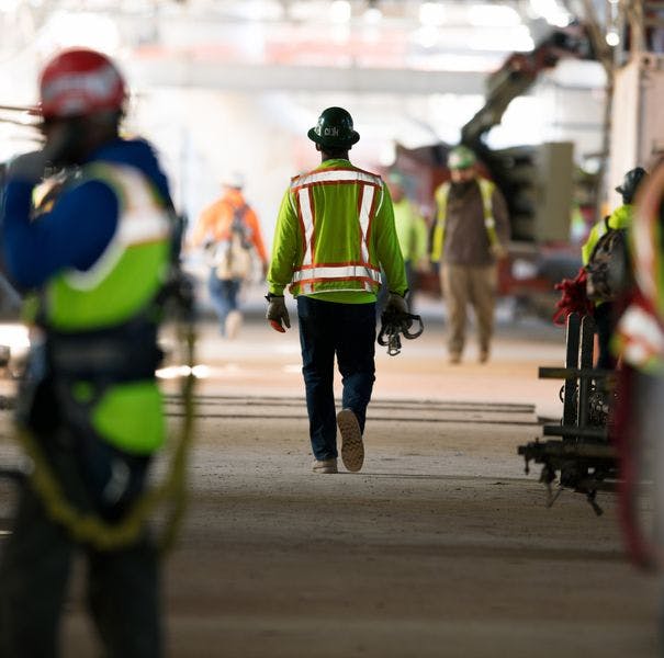 Photo of worker on project site walking away from viewer.