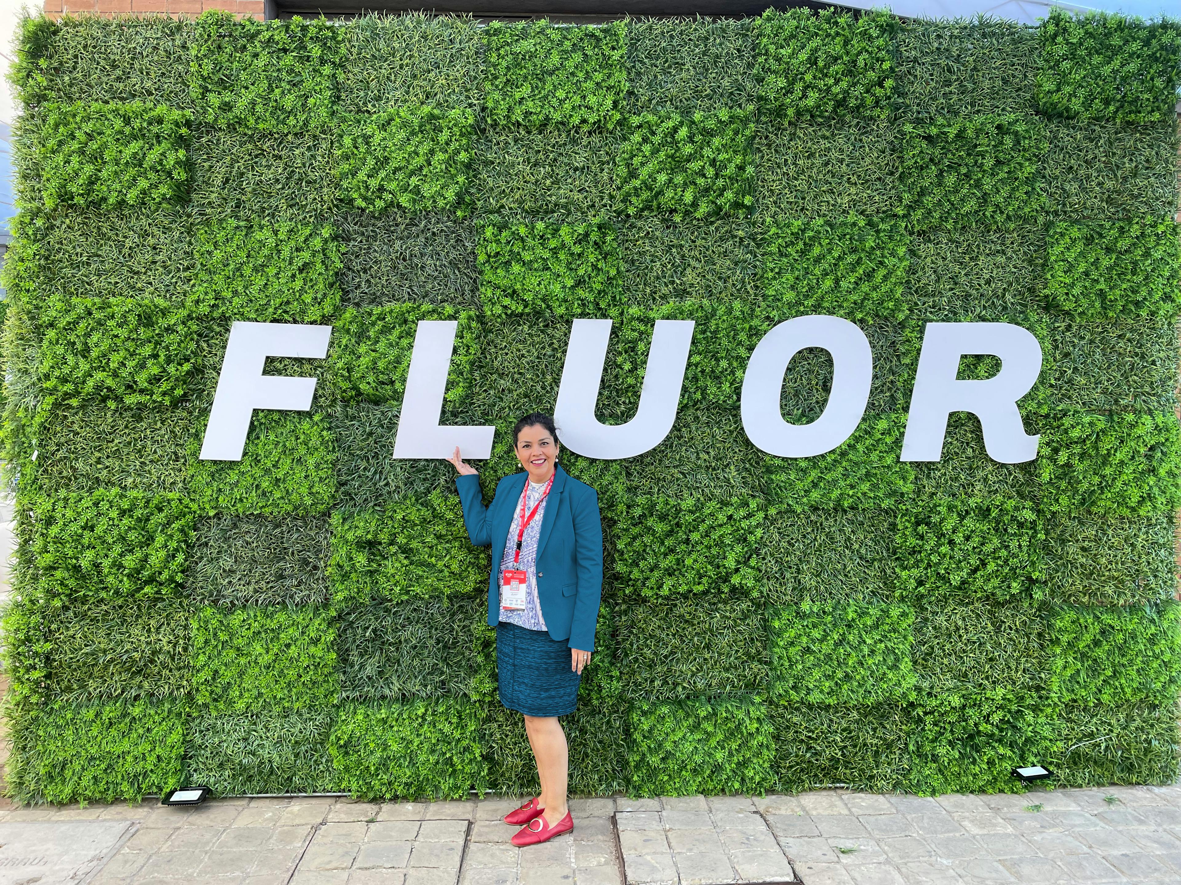 Woman standing in front of wall of plants with Fluor logo